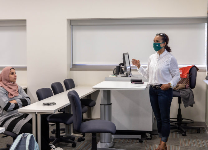 An Oakton professor stands in front of a classroom of students.