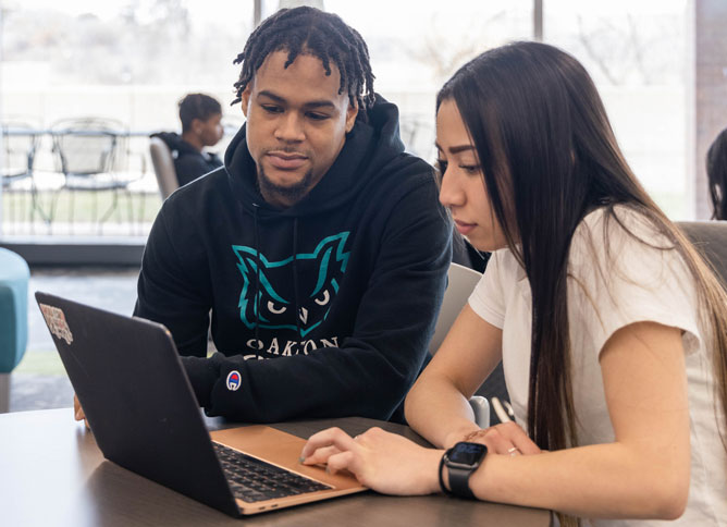 Two students working on a laptop.