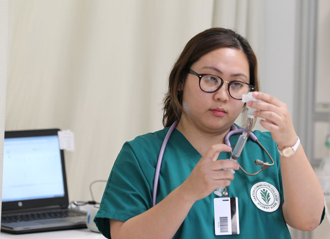 Student in scrubs preparing a vaccine.