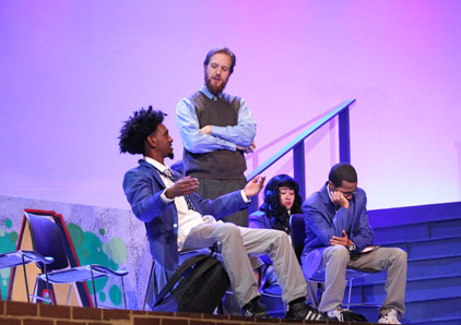 Oakton student sitting on stage.