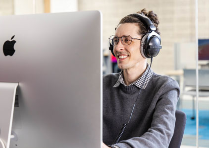 Student staring at computer screen with headphones on.